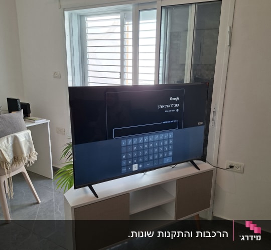 טלוויזיה על מזנון מול חלון עם תריסים